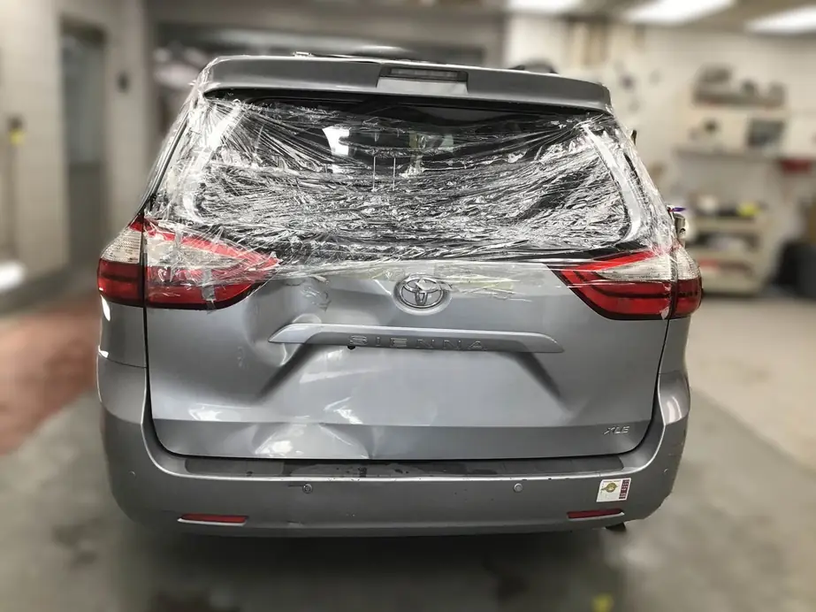Toyota Sienna with a smashed lift gate, wrapped and waiting for repair