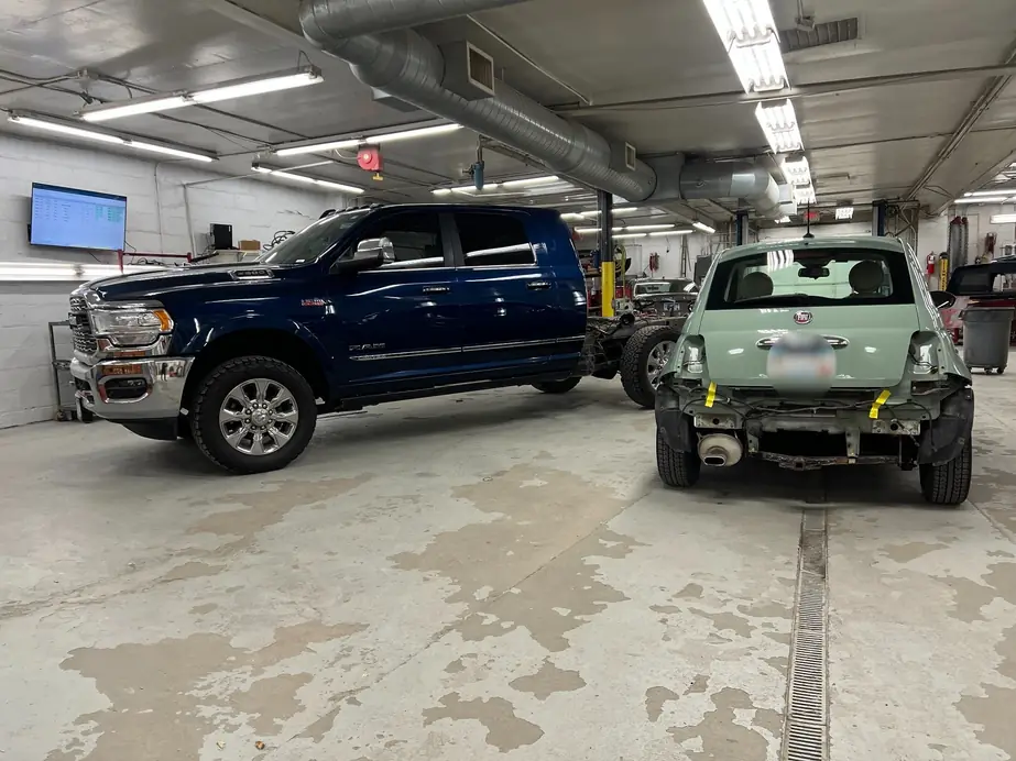 Navy pickup truck and a green Fiat mid-repair on the long shop floor at New Central