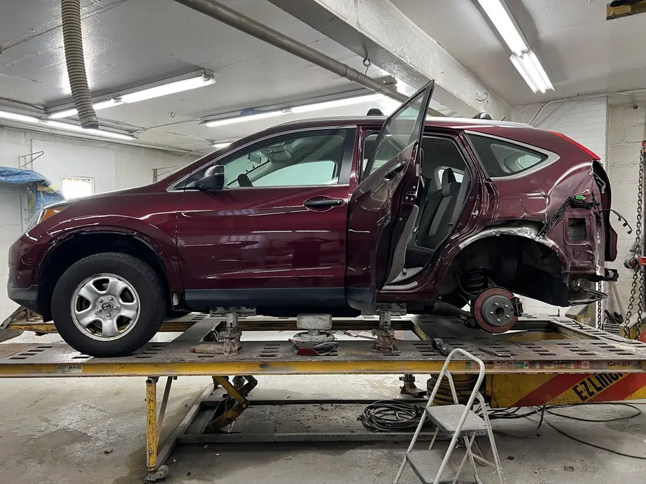 Maroon Honda CR-V mounted on the frame machine inside the New Central Auto Body shop