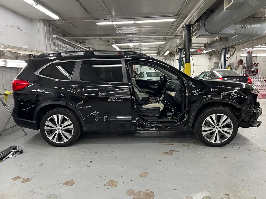 Black Subaru Ascent with its doors open, torn down in the bay to document the damage