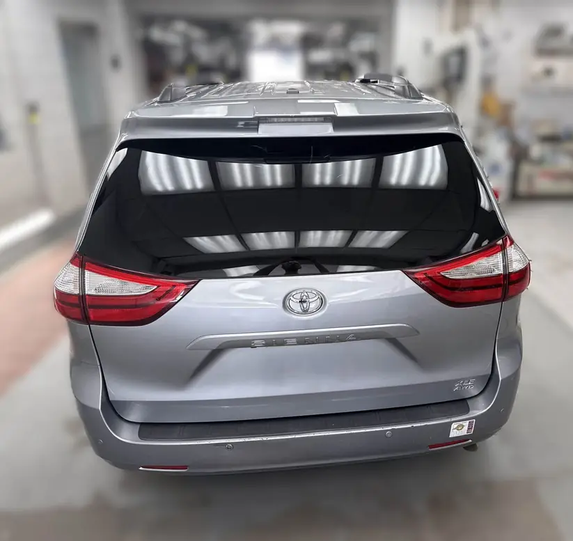 Repaired Toyota Sienna lift gate reflecting the booth lights after refinishing